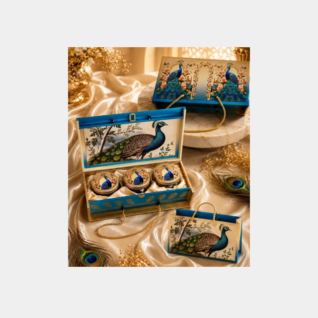 Teal peacock-motif Diwali box holding three dry fruit jars, decorative diyas and a greeting card