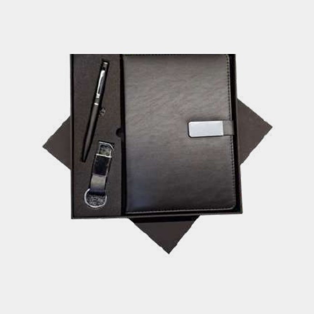 Charcoal notebook with slim metal pen and leather-strap keychain in a fitted tray