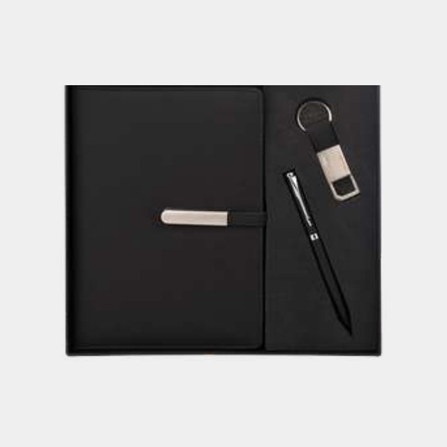 Black notebook with metal pen and leather-strap keychain in a fitted black tray